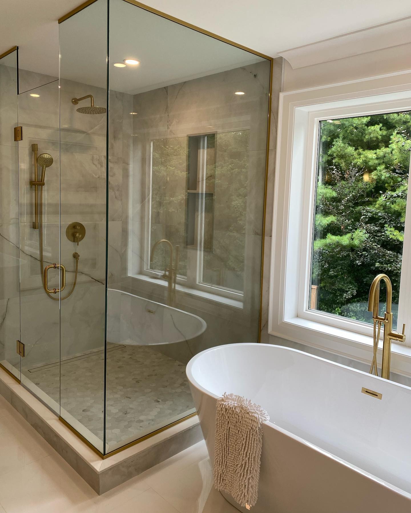 Luxury master ensuite with gold fixtures, freestanding tub and marble tile in Hamilton Ontario