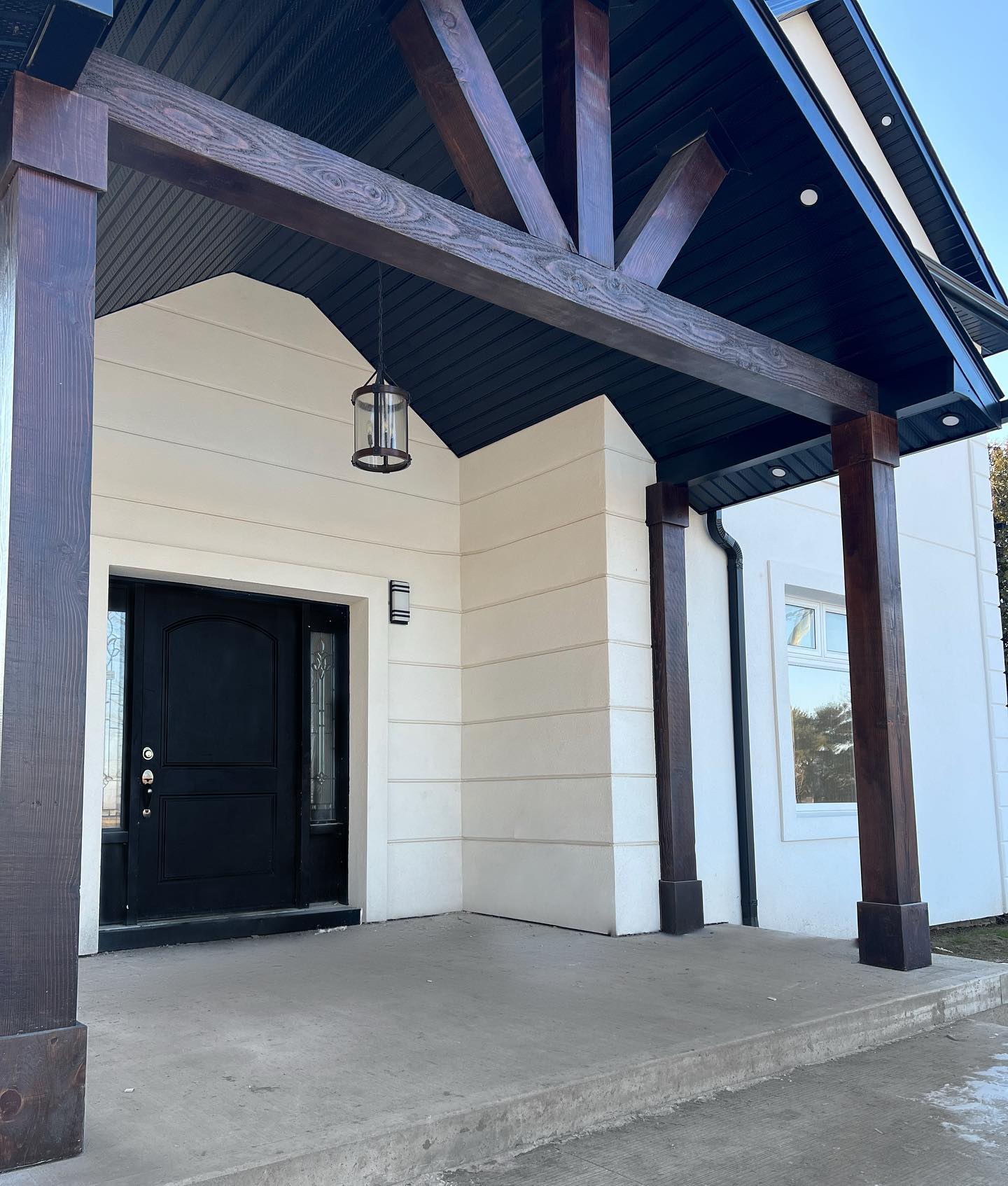 Custom timber beam entry portico with dark stained beams and black T&G soffit in Hamilton Ontario
