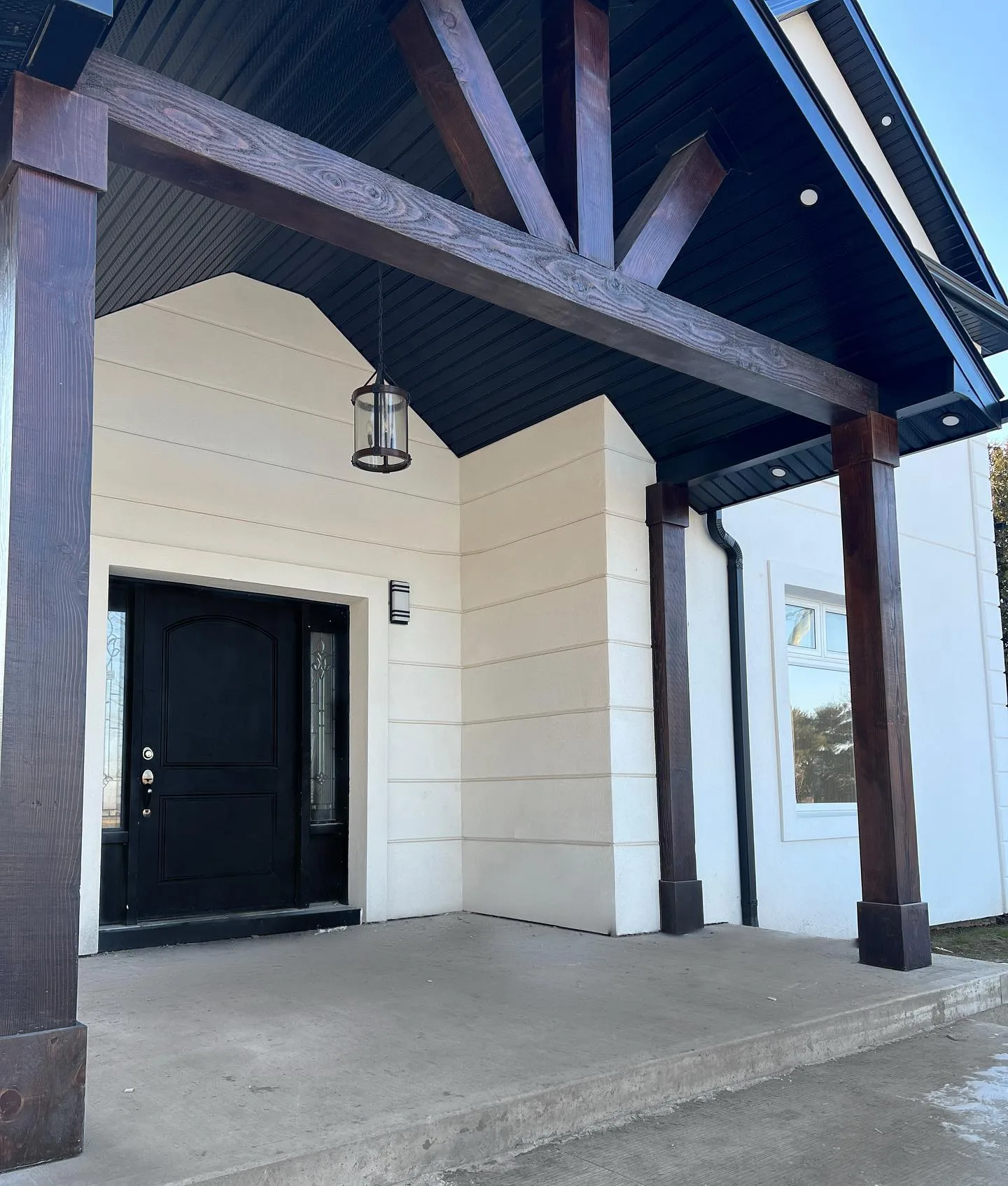 Custom timber beam entry portico with dark stained beams and black T&G soffit in Hamilton Ontario