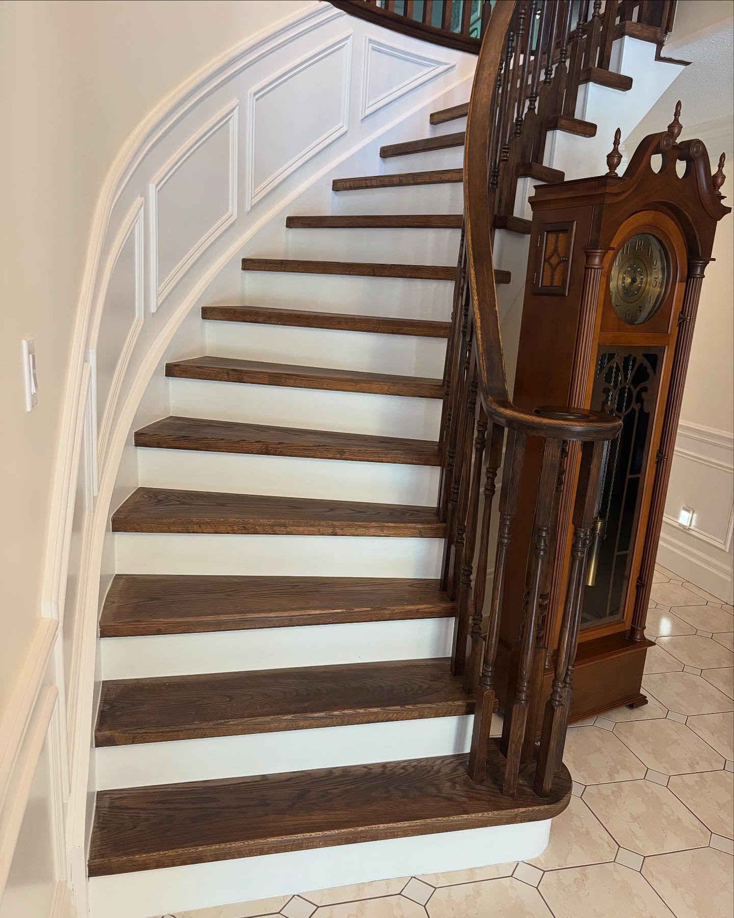 Curved heritage staircase with dark walnut treads and white wainscoting in Hamilton Ontario